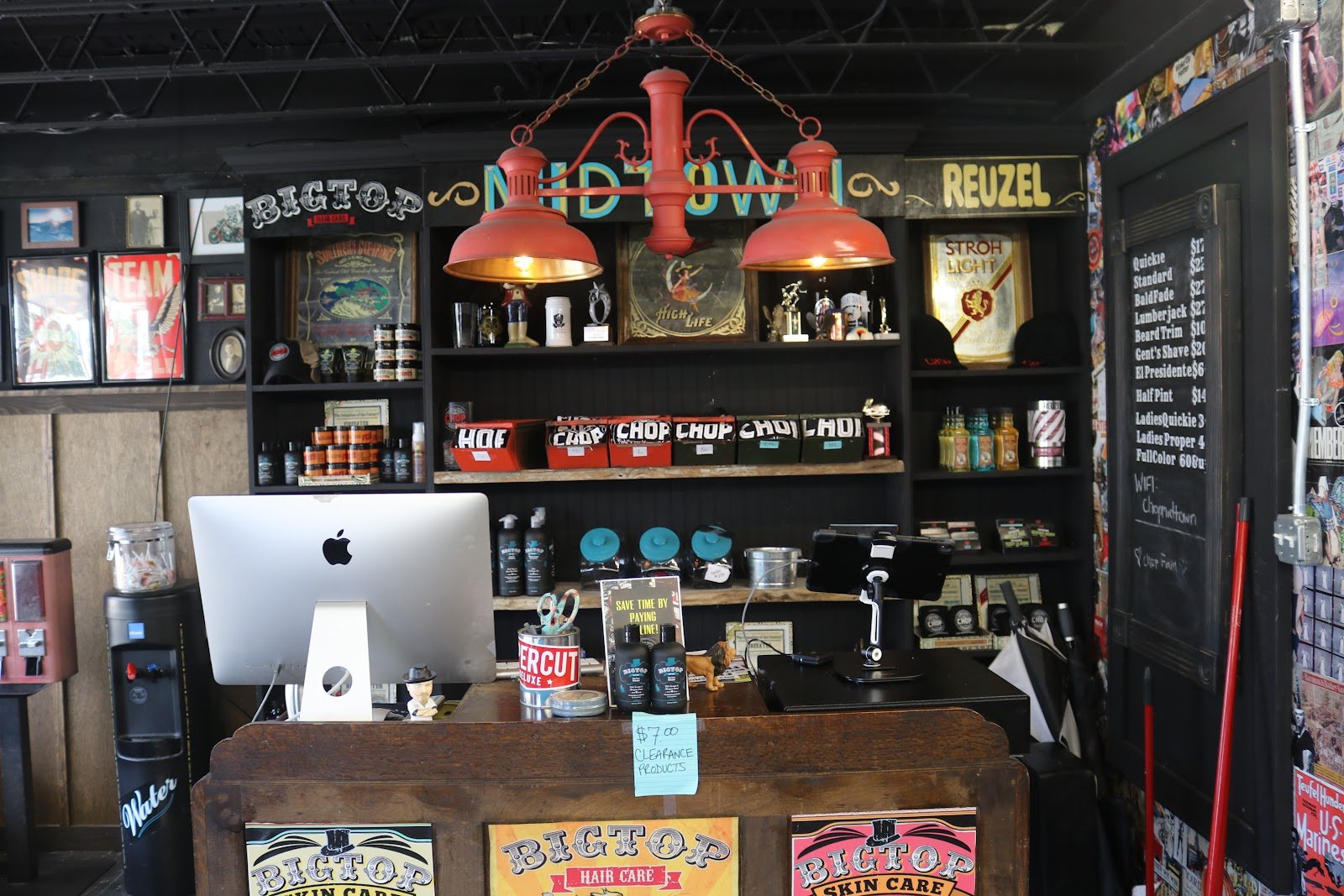 The front counter with a computer, shelves of hair products and a chalkboard behind it.