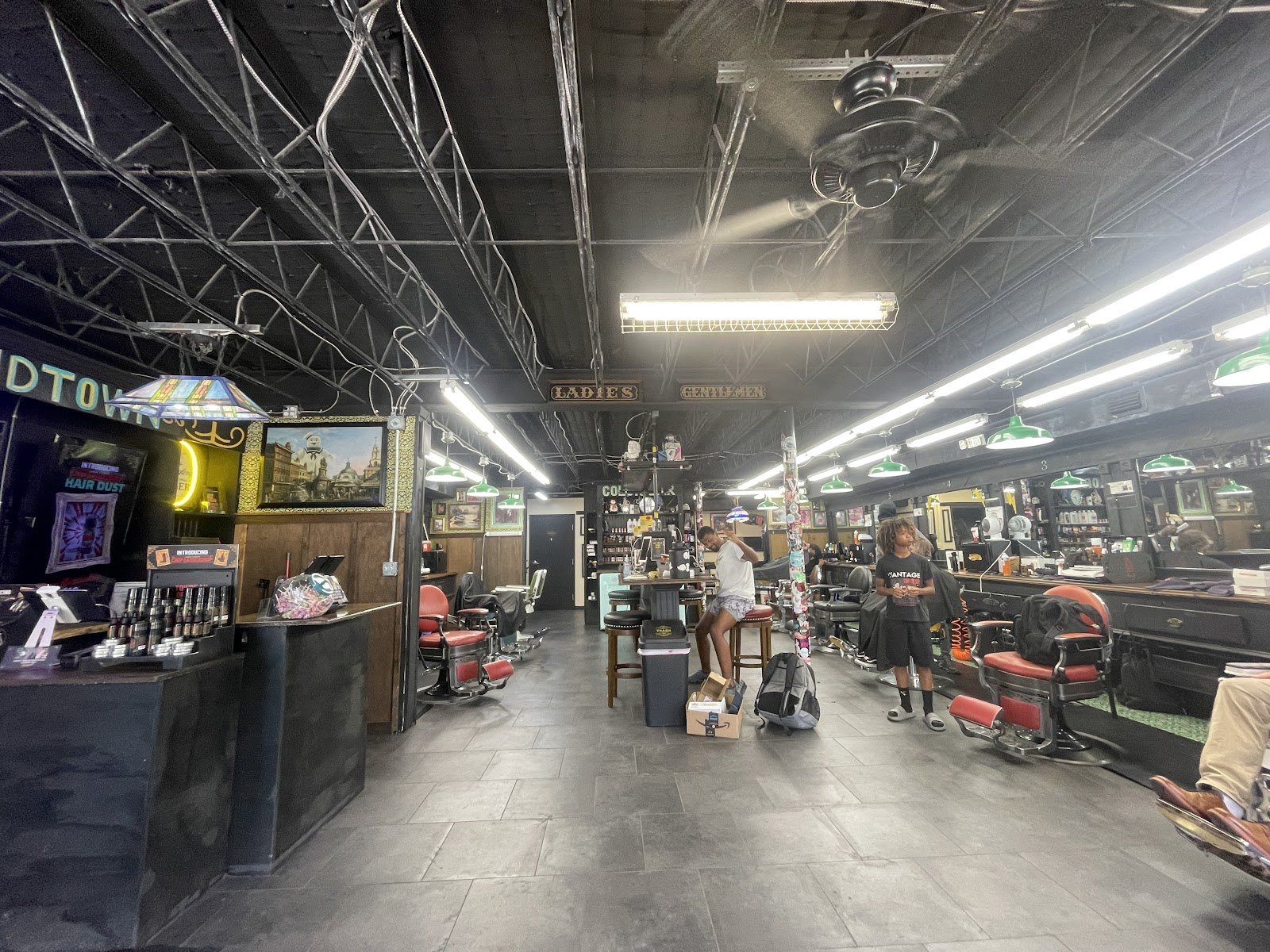 The shop floor from the door: barber chairs in a row under long warehouse lights.
