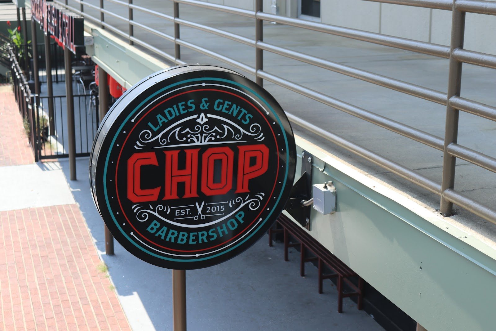 The round CHOP Barbershop sign mounted on the wall outside the shop.